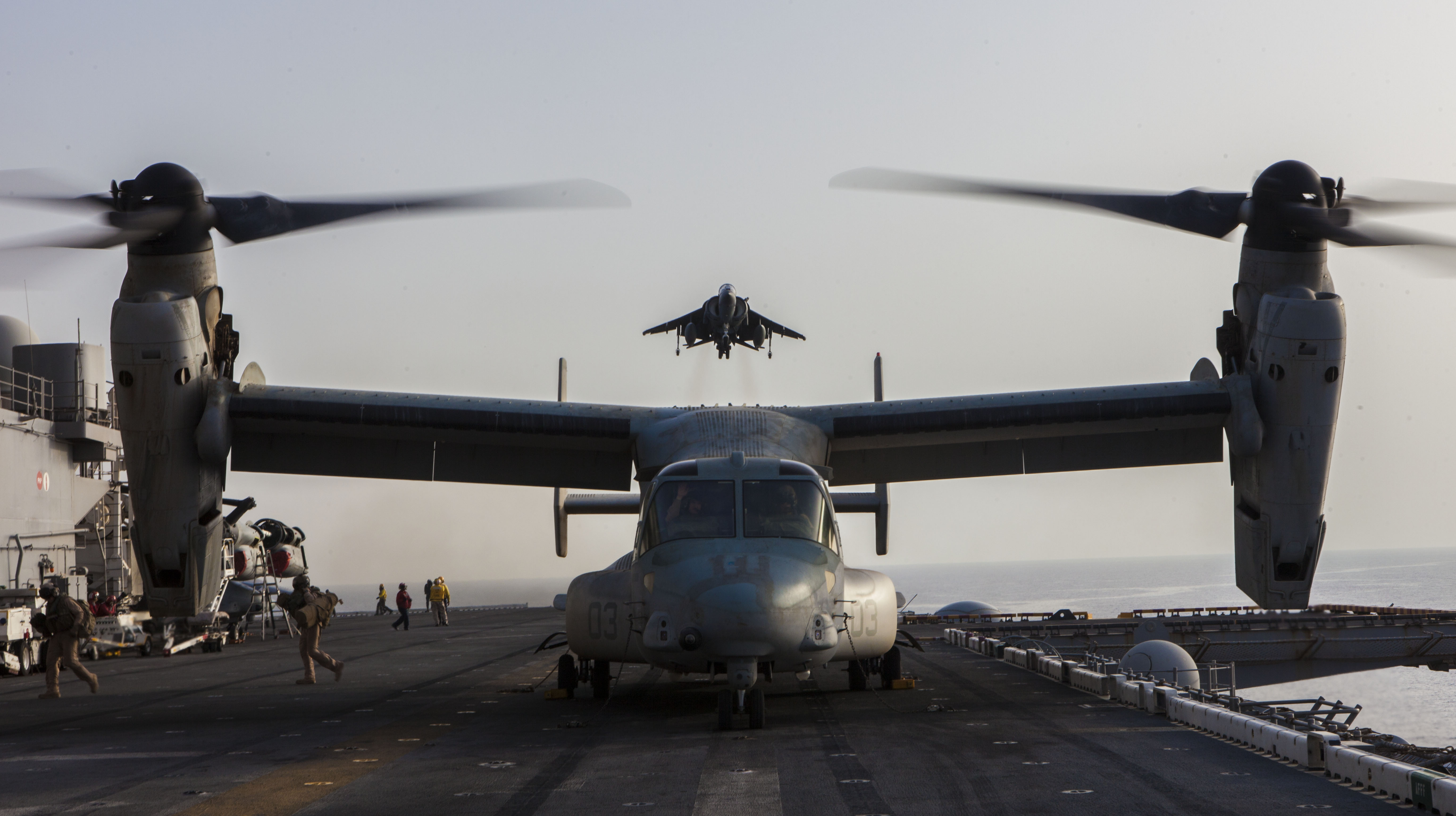 A U.S. Marine Corps AV-8B Harrier aircraft, top, assigned to Marine Medium Tiltrotor Squadron (VMM) 266 approaches the flight deck of the amphibious assault ship USS Kearsarge (LHD 3) as an MV-22B Osprey tiltrotor aircraft prepares to take off May 27, 2013, in the U.S. 5th Fleet area of responsibility. (DoD photo by Sgt. Christopher Q. Stone, U.S. Marine Corps/Released)